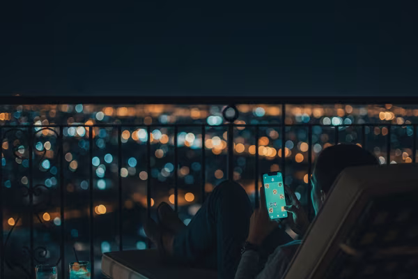 Traveller playing a phone game on a hotel balcony at night