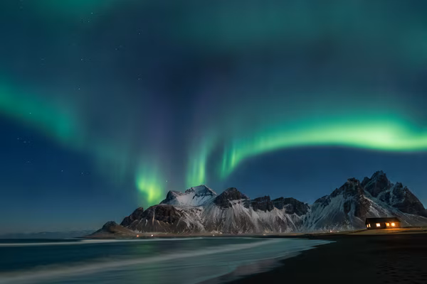 Northern lights over Iceland mountains and a cabin
