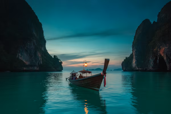 Longtail boat among Krabi limestone cliffs at twilight