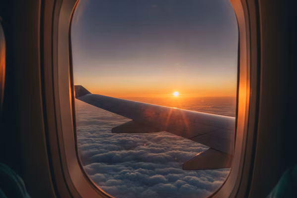 Airplane wing above sunset clouds