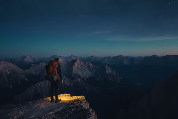 Solo traveller overlooking a mountain valley at blue hour