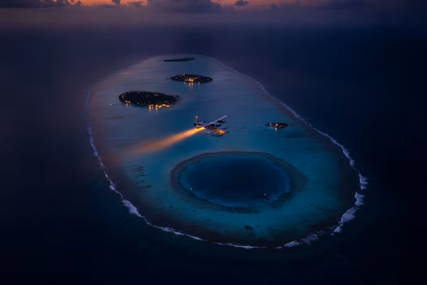 Seaplane over Maldivian atolls at golden dusk