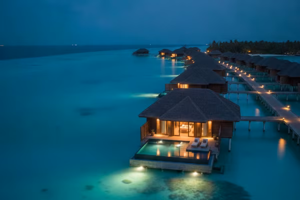 Overwater villa with private infinity pool at dusk
